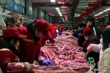 客対応をする北京の市場の豚肉販売員ら＝2日（ロイター＝共同）