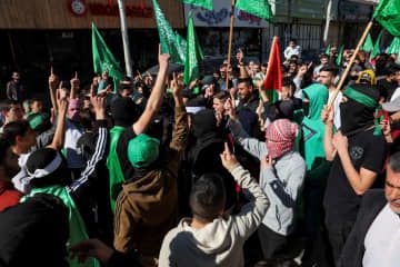 ハマスの旗を持つパレスチナ人＝2023年11月、ヨルダン川西岸（ロイター＝共同）