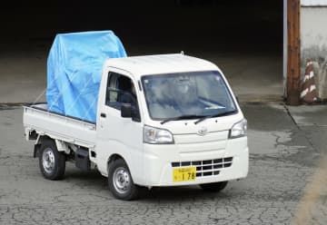 ブルーシートで覆われた、箱わなに入ったクマを運び出すトラック＝9日午前、秋田市