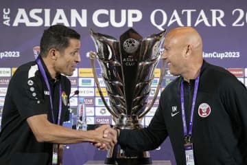 サッカーアジア杯の決勝戦を前に、握手を交わすヨルダンのアムータ監督（左）とカタールのロペス監督＝ドーハ（共同）