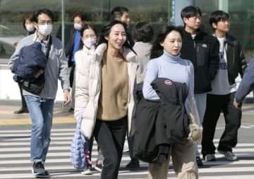 高気圧の影響で気温が上昇し、上着を手に持ち歩く人たち＝13日午後、福岡市