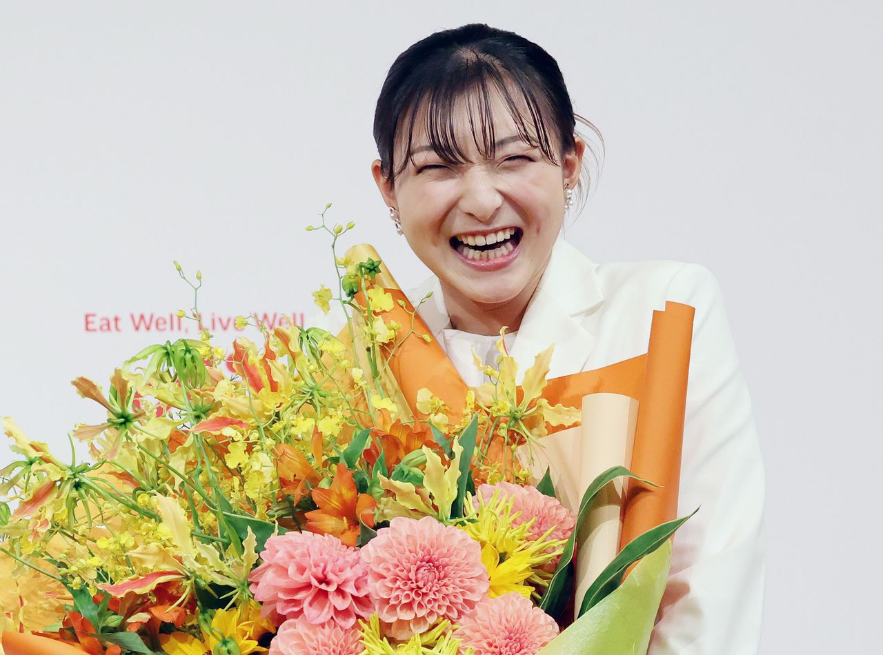 花束を手に笑顔を見せるフィギュアスケート女子の坂本花織さん。記者会見で結婚を発表した=2026年5月13日、神戸市中央区 (時事)