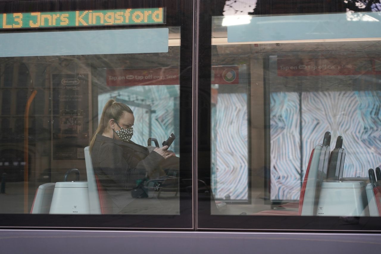 6月27日、オーストラリアで新型コロナウイルスの新規感染者数が今年最多を記録し、最大都市シドニーと北部の都市ダーウィンでロックダウンが始まったほか、4つの州が行動規制を強化した。写真は26日、シドニーでマスクを着用する女性(2021年 ロイター/Loren Elliott)