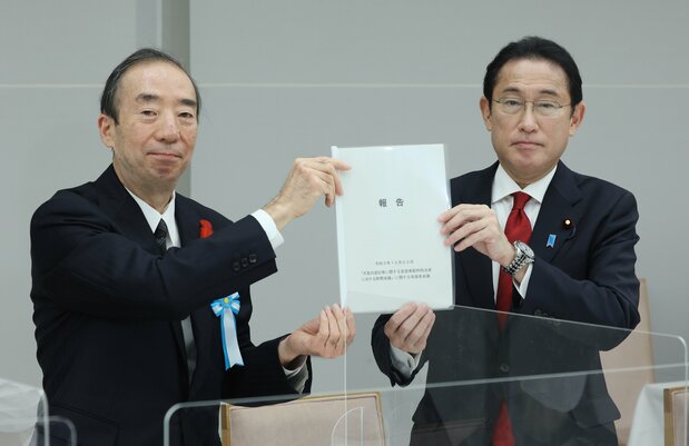 2021年12月22日，岸田文雄首相在首相官邸，从讨论皇位稳定继承方案的专家委员会主席清家笃（左）手中接过最终报告书（图片：时事社）