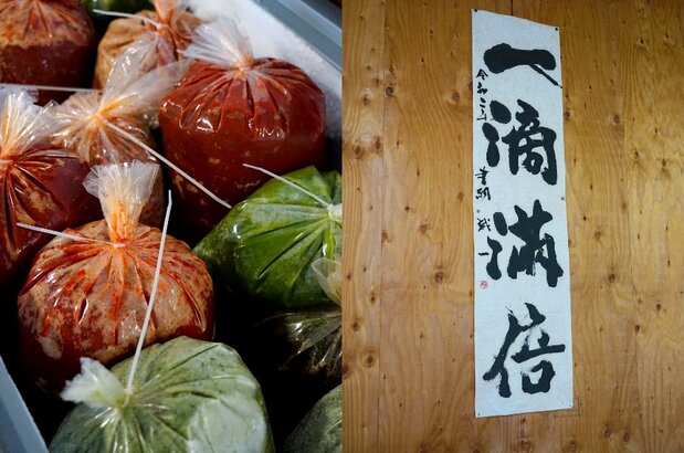 A la izquierda: una variedad de pasta de chile congelada. A la derecha, un lema escrito de puño y letra por Hirai: Itteki manbai, o “De una sola gota, abundantes frutos”. (© Ukita Yasuyuki)