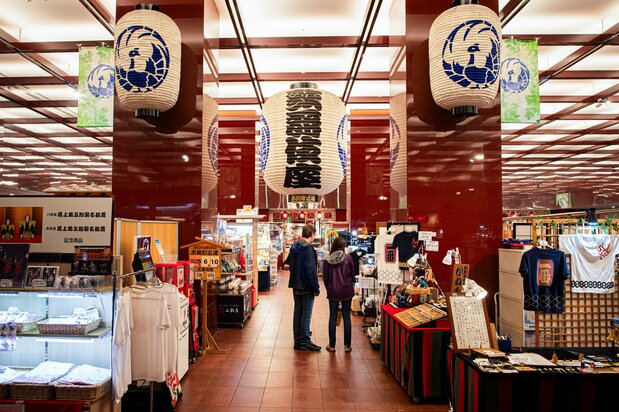 歌舞伎座的必买伴手礼，包括印有脸谱图案的文件夹、手帕，以及印有《劝进帐》《义经千本樱》等经典剧目人物图案的仙贝“歌舞伎狂言煎饼”