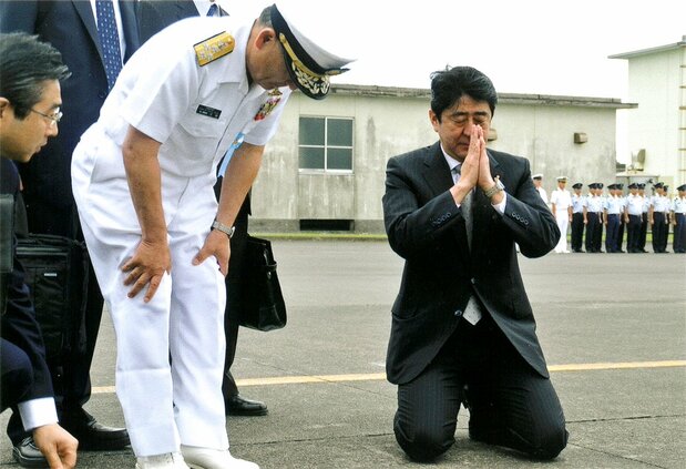安倍首相(右)视察众多战死日本士兵长眠的硫磺岛,在飞机跑道上突然跪地合掌,海上幕僚长河野克俊(左起第2人)在其身旁(河野提供)