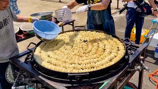 透过活动积极推广圆盘饺子。在巨大平底锅上放满700颗饺子，现场展示煎圆盘饺子（福岛饺子之会提供）