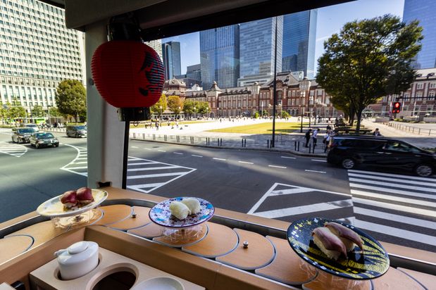 The sushi plates glide by to the backdrop of Tokyo Station and other iconic sights. (© Nippon.com)