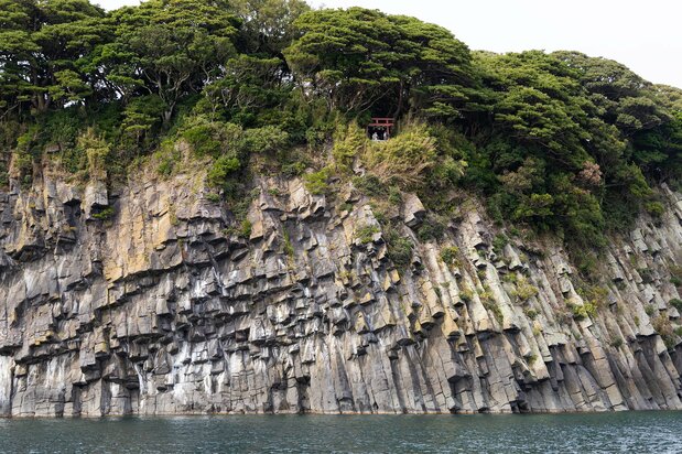 在“蜂巢岩”的崖壁上方，可以看到大凑神社的红色鸟居