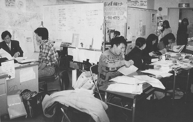 田村太郎(左二)开设的“外国人地震信息中心”。1995年手机与网络尚未普及,他们通过传单、报纸、广播来宣传咨询热线电话(多样性研究所提供)