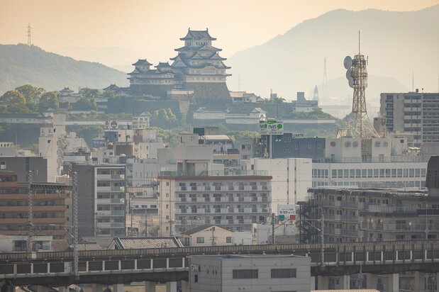 从手柄山中央公园的观景台，眺望电车线路和街区远方笼罩在晨雾中的天守。建于江户初期的姬路城，仿佛正在守护着这座现代都市