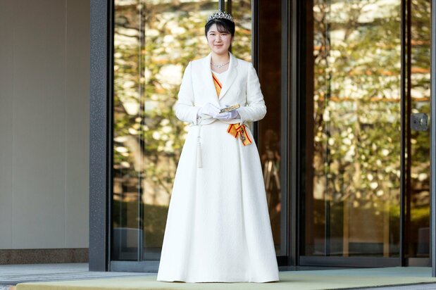 德仁天皇和皇后的长女爱子公主佩戴头冠和勋章，身着正装礼服，出席成人礼活动（2021年12月5日于皇居 宫殿西门，记者团代表摄影，路透社）