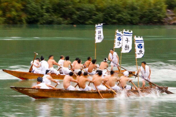 川の流れに逆らって11人で船を進める