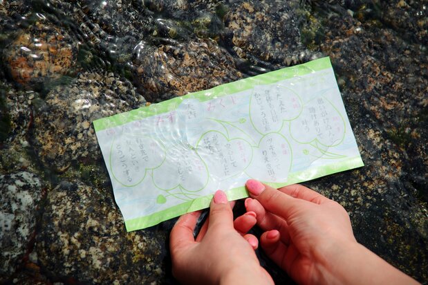 在御手洗授与所求到的“水神签”。上面印着下鸭神社的神纹双叶葵，浸入池水中则浮现出预测运势的文字，等待结果的过程既紧张也令人期待