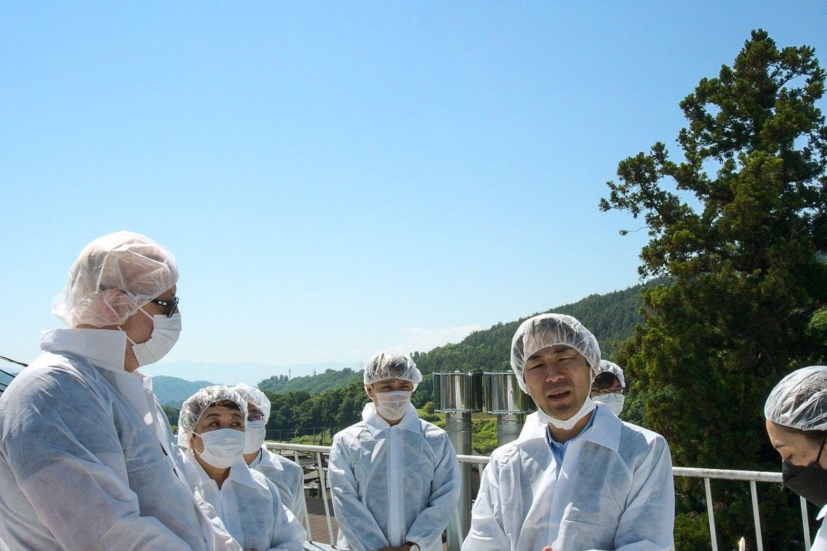Китахара Цусима (в спущенной маске) обсуждает производство сакэ с членами Wine and Spirit Education Trust на фоне Южных Японских Альп (© Джим Рион)