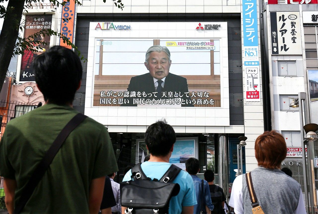 Люди смотрят видеообращение императора Акихито к народу 8 августа 2016 г. в токийском районе Синдзюку (Jiji Press)