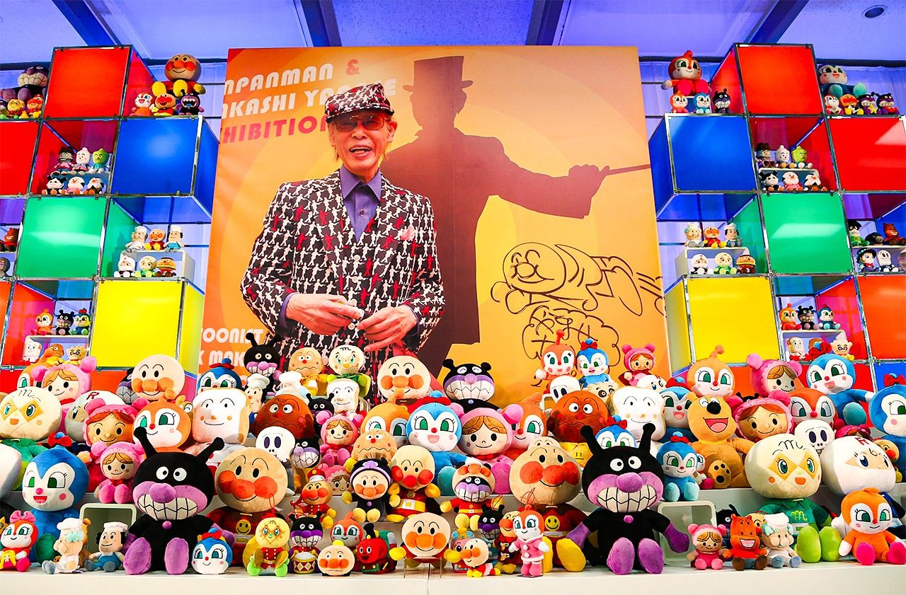 Плакат с изображением Янасэ Такаси, окружённого куклами персонажей из сериала «Анпанман», на вечере памяти 6 февраля 2014 года в Синдзюку, Токио (© Jiji)