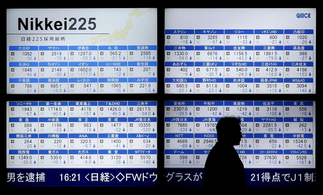 A man walks past an electronic board showing Japan