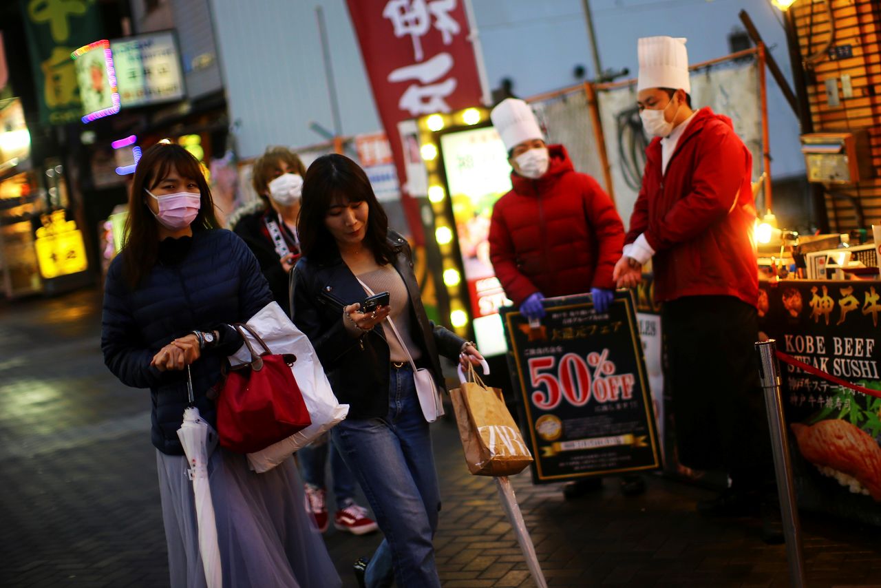 People, wearing protective masks following an outbreak of the coronavirus disease (COVID-19), walk on an almost empty street in the Dotonbori entertainment district of Osaka, Japan, March 14, 2020. Pictured taken March 14, 2020. REUTERS/Edgard Garrido