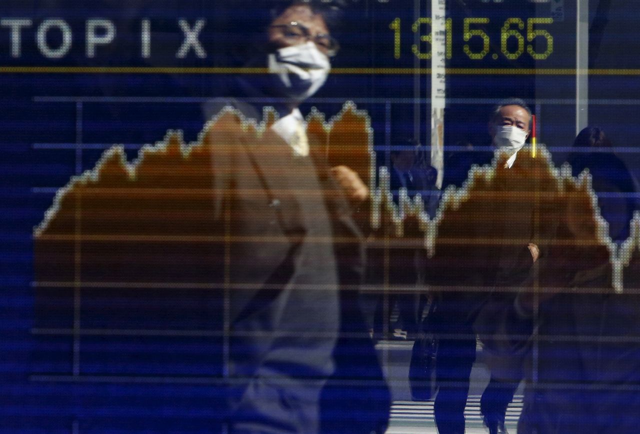 Pedestrians wearing masks are reflected in an electronic board showing the graph of the recent fluctuations of the Tokyo Stock Price Index (TOPIX) outside a brokerage in Tokyo, Japan, February 26, 2016. REUTERS/Yuya Shino