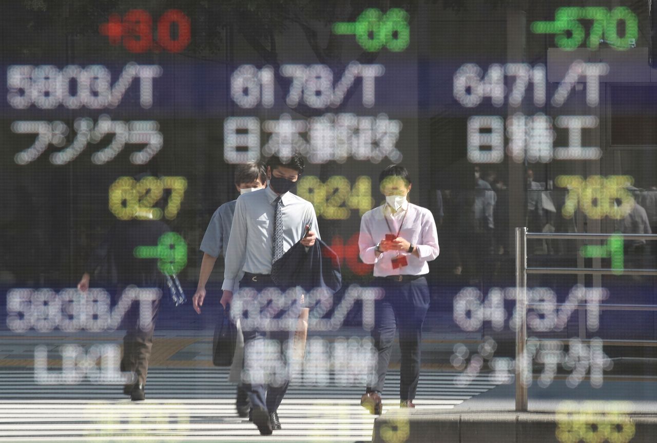 People wearing protective masks, amid the coronavirus disease (COVID-19) outbreak, are reflected on an electronic board displaying Japan