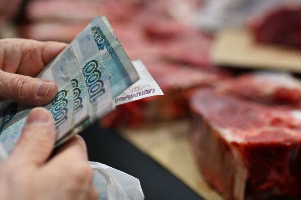 A customer holds Russian rouble banknotes in a meat stall at a market in Omsk, Russia October 29, 2021. REUTERS/Alexey Malgavko