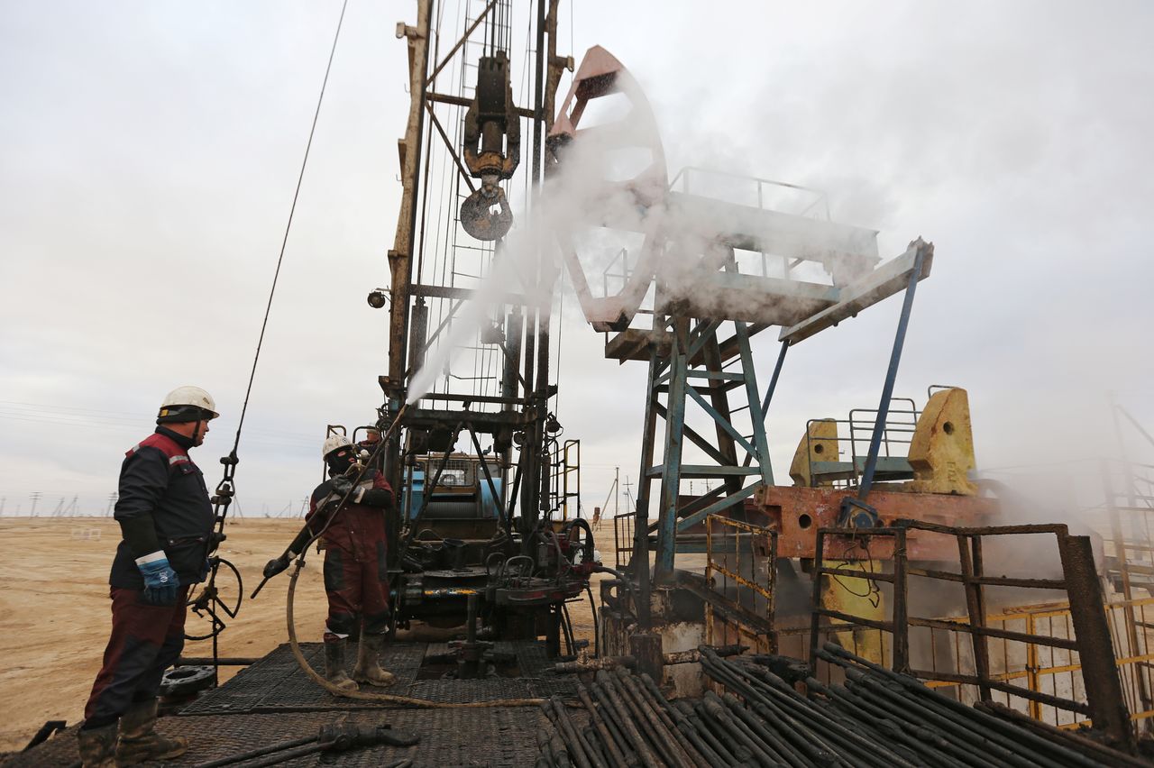 Workers use a steam jet to clean an oil pump in the Uzen oil and gas field in the Mangistau Region of Kazakhstan November 13, 2021. Picture taken November 13, 2021. REUTERS/Pavel Mikheyev