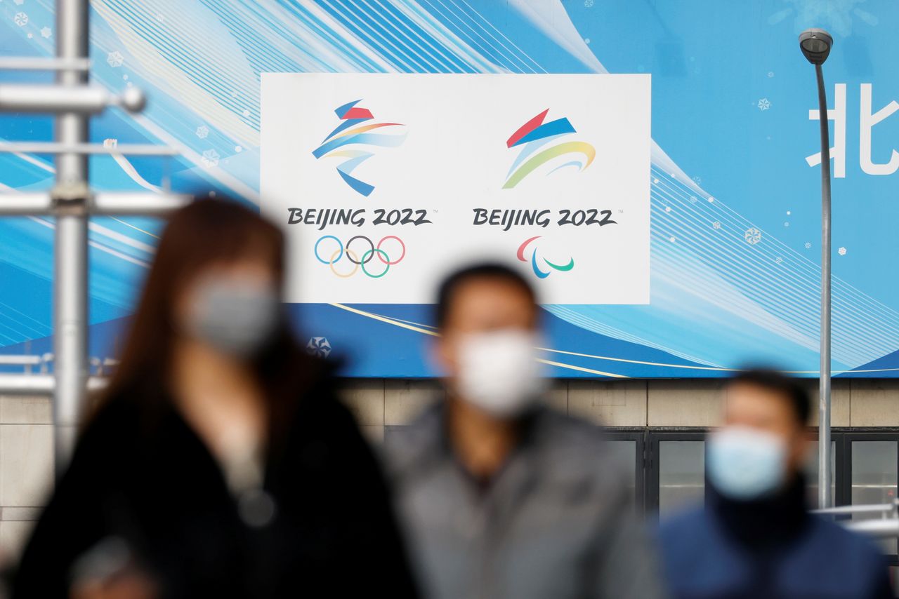 Pedestrians walk past the emblems of Beijing 2022 Winter Olympic and Paralympic Games near a flagship merchandise store for the Beijing 2022 Winter Olympics in Beijing, China December 8, 2021. REUTERS/Carlos Garcia Rawlins