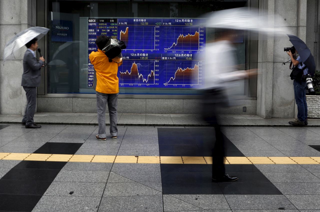 Videographer films an electronic board showing the graphs of exchange rates between the Japanese yen, the U.S. dollar and Euro outside a brokerage in Tokyo, Japan, July 6, 2015. The euro and stock prices fell sharply in Asia on Monday after the Greeks had overwhelmingly rejected austerity measures demanded in return for bailout money, putting in doubt its continued place in the single currency. U.S. equity futures dropped around 1.4 percent while Japan