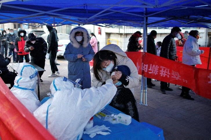 A medical worker in protective suit collects a swab from a resident for nucleic acid testing at a makeshift testing site for the coronavirus disease (COVID-19), after local cases of the Omicron variant were detected in Tianjin, China January 11, 2022. Picture taken January 11, 2022. cnsphoto via REUTERS   ATTENTION EDITORS - THIS IMAGE WAS PROVIDED BY A THIRD PARTY. CHINA OUT.