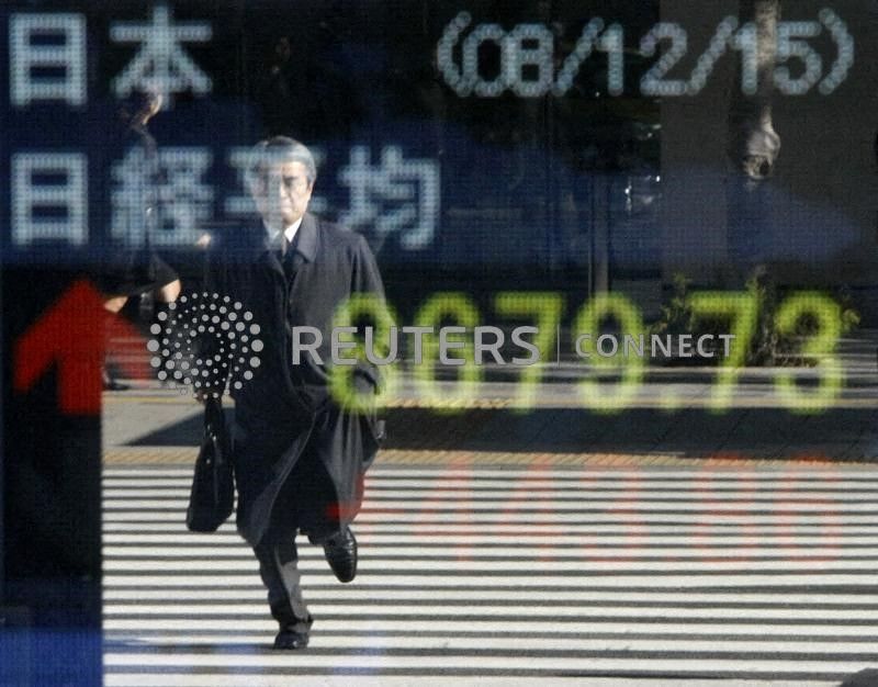 A man is reflected in a board showing the current Nikkei average outside a brokerage in Tokyo December 15, 2008. REUTERS/Toru Hanai