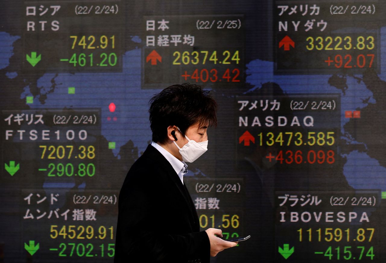 A man wearing a protective mask, amid the coronavirus disease (COVID-19) outbreak, walks past an electronic board displaying Russian Trading System (RTS) Index, Japan