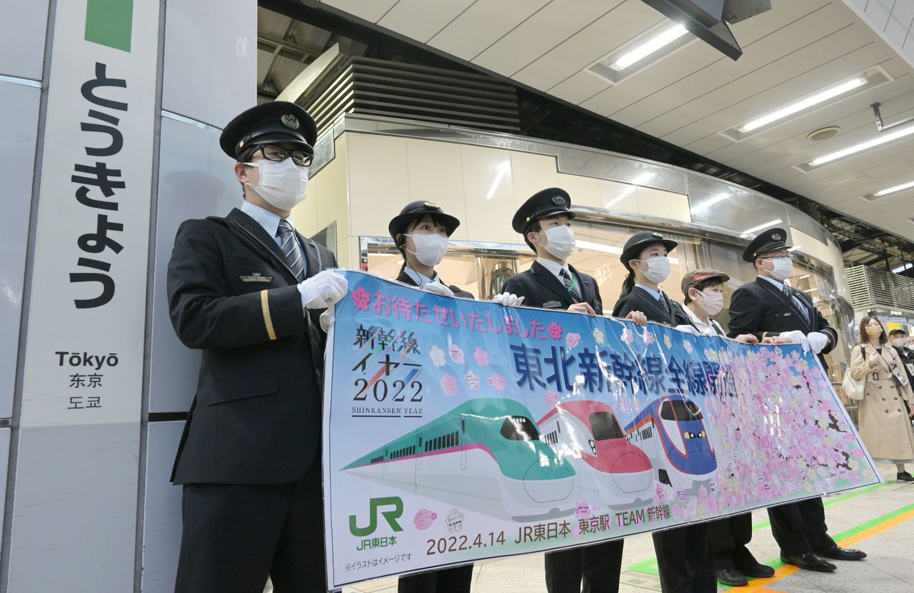 Служащие компании JR East (JR Хигаси Нихон) с транспарантом о возобновлении движения по всей линии Тохоку синкансэн, 14 апреля 2022 г. (© Jiji Press)