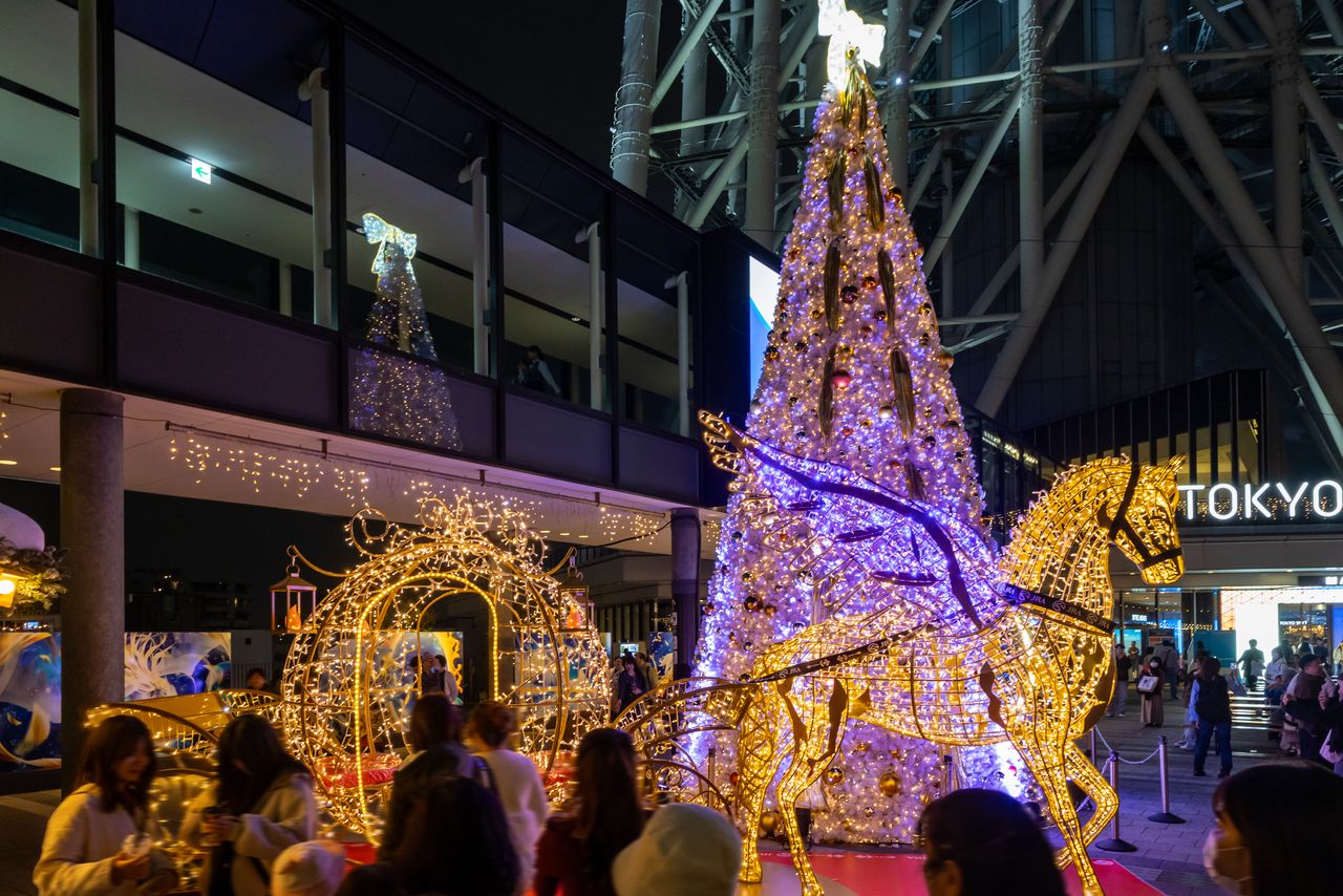 Посетители выстраиваются в очередь, чтобы сфотографироваться перед каретой Пегаса и восьмиметровой рождественской ёлкой на площади (© Nippon.com)