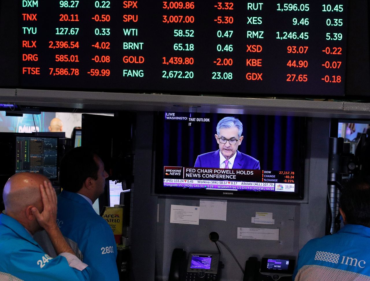 FILE PHOTO: Traders look on as a screen shows Federal Reserve Chairman Jerome Powell