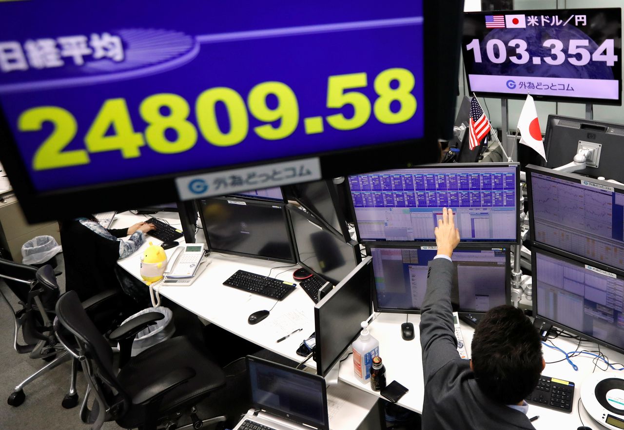 An employee of the foreign exchange trading company works in front of monitors showing Japan