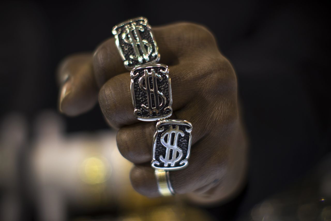 A man wears U.S. dollar sign rings in a jewellery shop in Manhattan in New York City November 6, 2014. A year-long investigation into allegations of collusion and manipulation by global currency traders is set to come to a head on Wednesday, with Britain