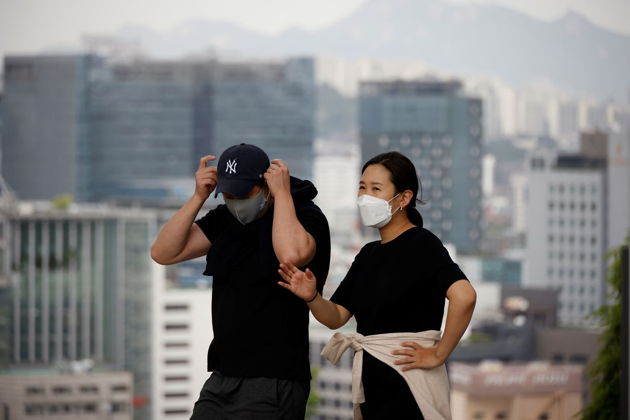 A couple wearing masks to avoid contracting the coronavirus disease (COVID-19) take a walk at a park in Seoul, South Korea, May 26, 2021. REUTERS/Kim Hong-Ji