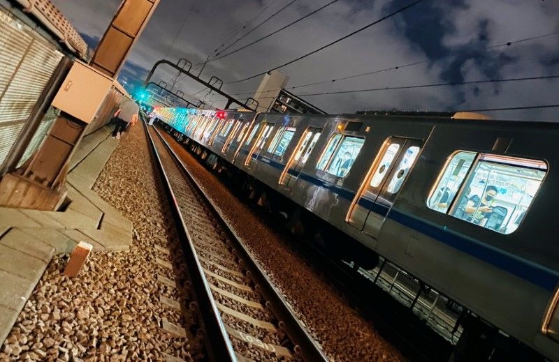 Люди идут по железнодорожным путям после нападения с ножом в поезде в Токио, Япония, 6 августа 2021 г. Снимок получен из социальных сетей. TWITTER / _KING_OF_SKY / через REUTERS