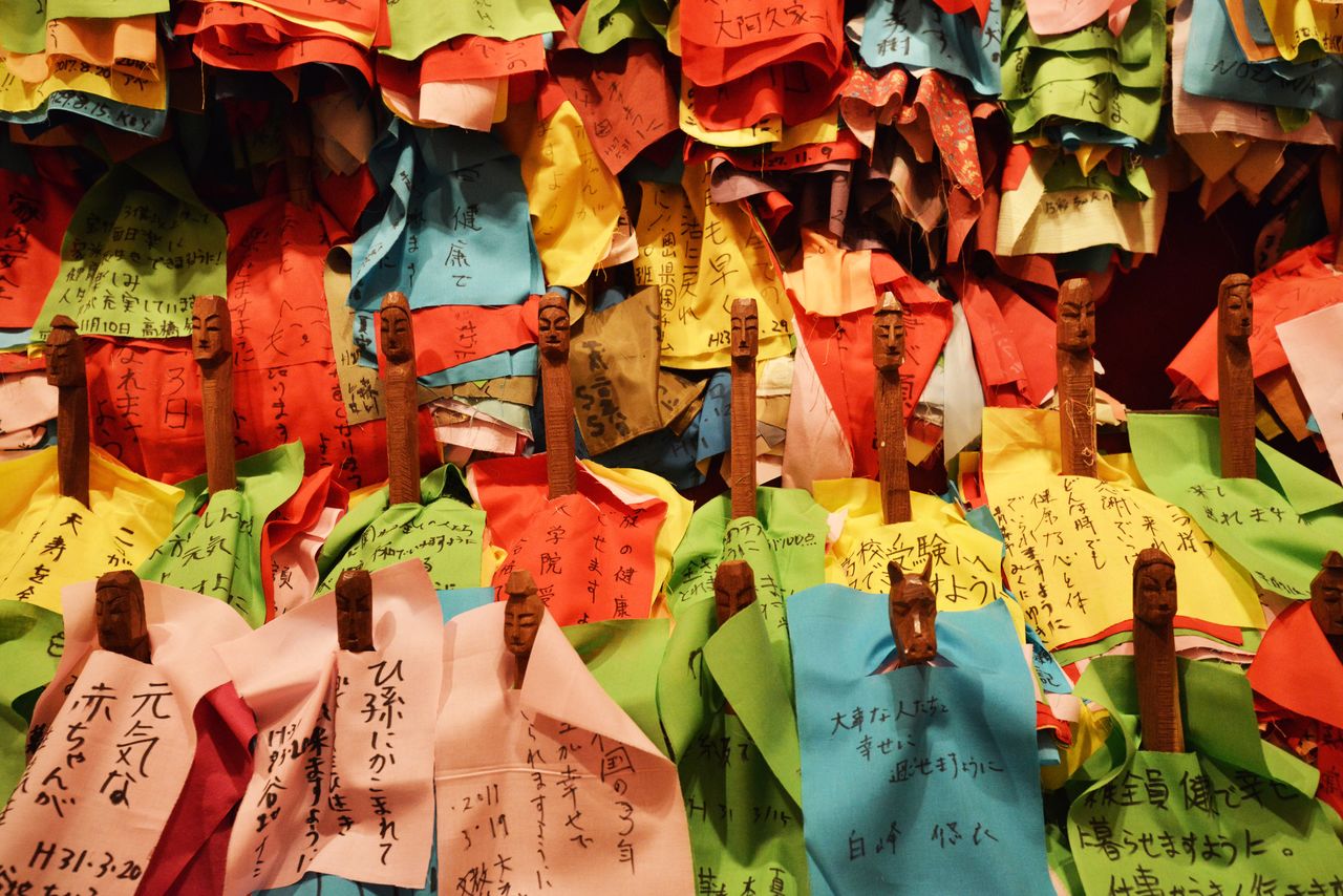 木彫りの人形に願いごとが書かれた布地が着せてある