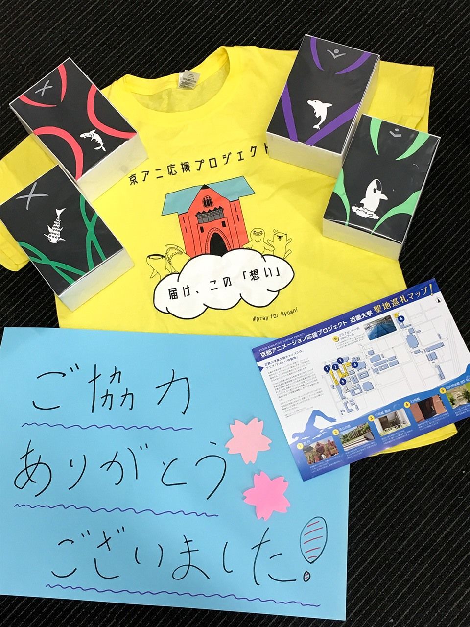 近畿大学の京アニ応援イベントに使ったスタッフのTシャツなど。募金した人には東大阪キャンパスの「聖地巡礼マップ」も配布した