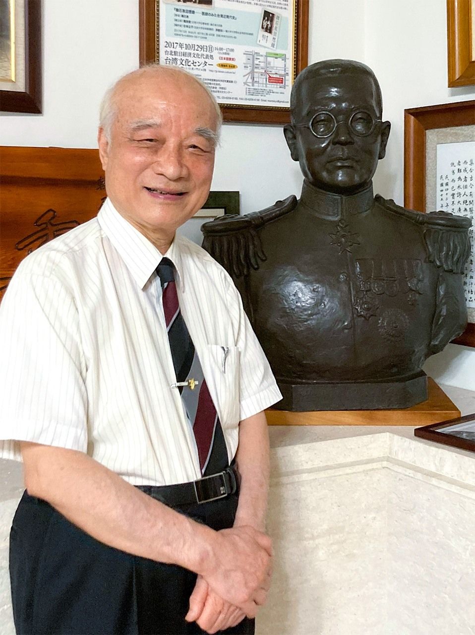 韓良誠院長。父の恩師・堀内次雄校長の銅像前で(筆者撮影)